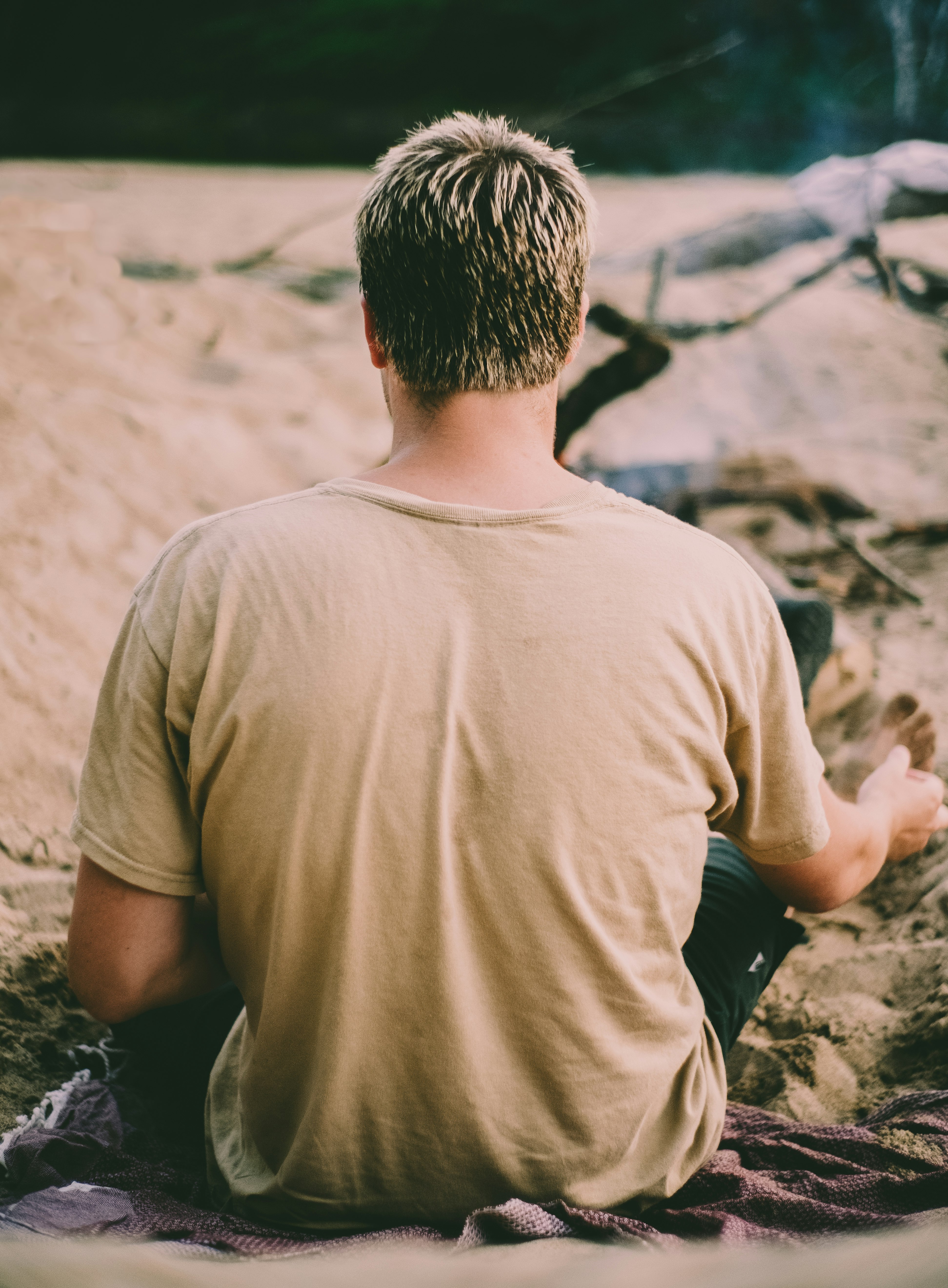 man in brown crew neck t-shirt sitting on rock during daytime